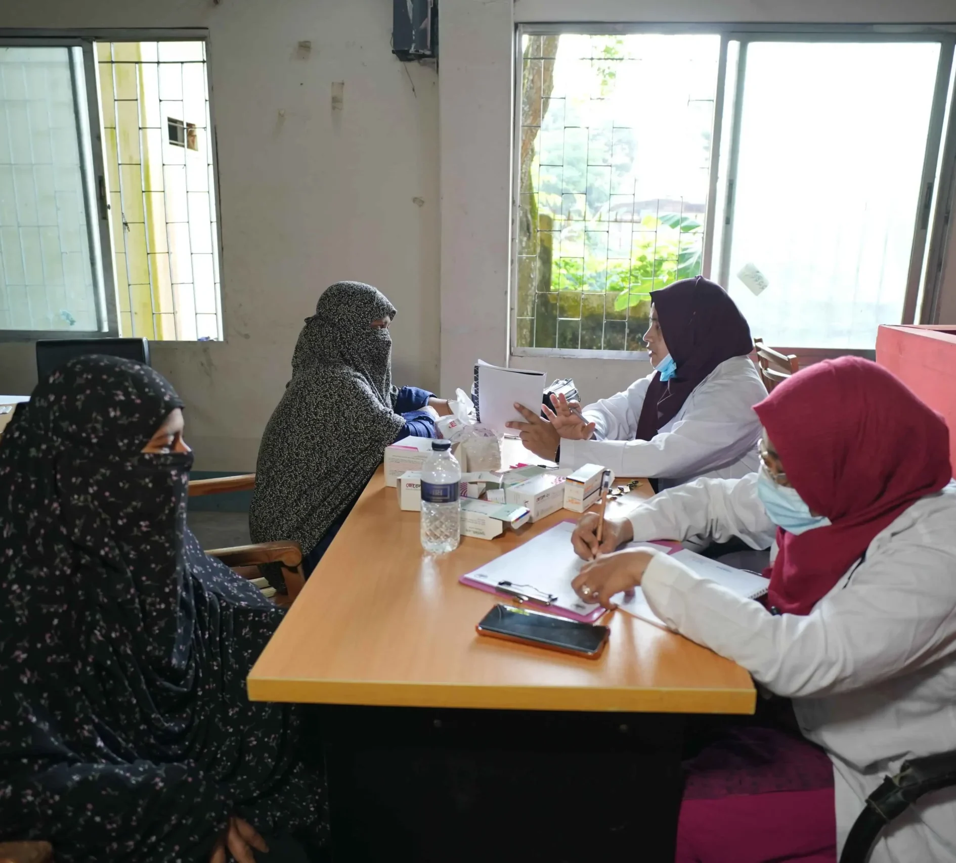 A clinician examining a patient at a community medical camp while others wait